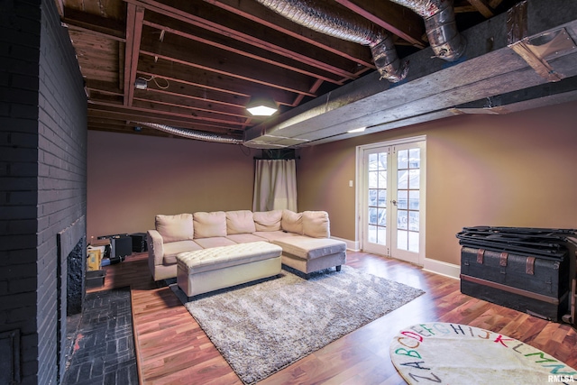 living area with french doors, a brick fireplace, wood finished floors, and baseboards