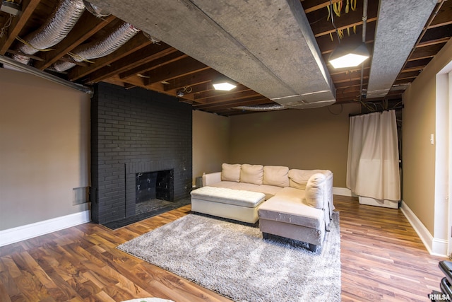 living area featuring a brick fireplace, baseboards, and wood finished floors