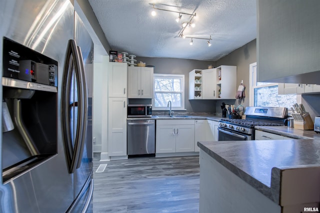 kitchen featuring stainless steel appliances, white cabinets, a sink, and a textured ceiling