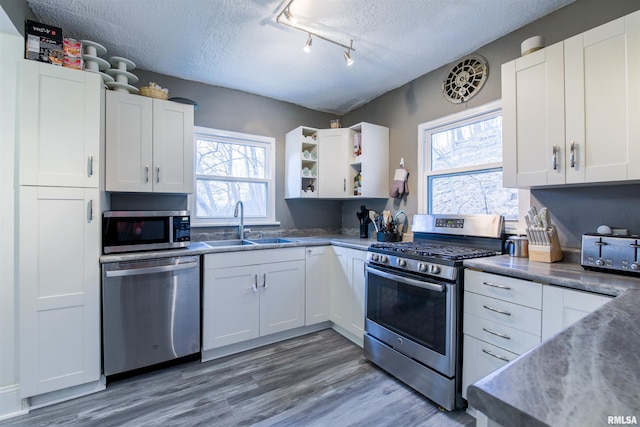 kitchen featuring a textured ceiling, stainless steel appliances, a sink, and white cabinetry