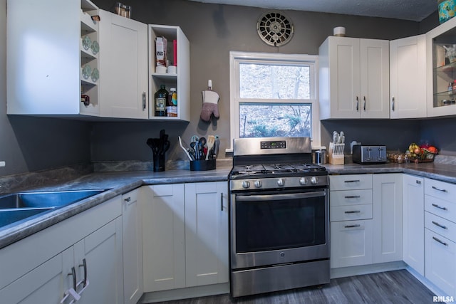 kitchen with open shelves, dark wood finished floors, gas range, and white cabinets