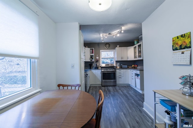 kitchen featuring dark wood-style floors, dark countertops, glass insert cabinets, white cabinets, and stainless steel gas range