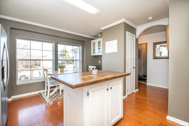 kitchen featuring arched walkways, light wood-style flooring, white cabinets, butcher block countertops, and stainless steel fridge with ice dispenser