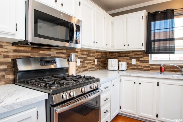 kitchen with a wealth of natural light, white cabinetry, appliances with stainless steel finishes, and a sink