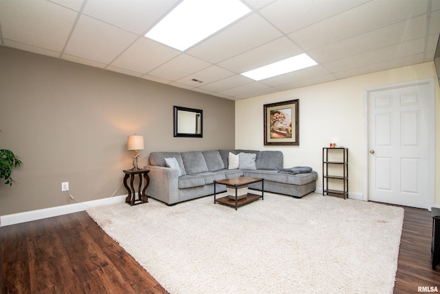 living area with dark wood-style flooring, a paneled ceiling, and baseboards