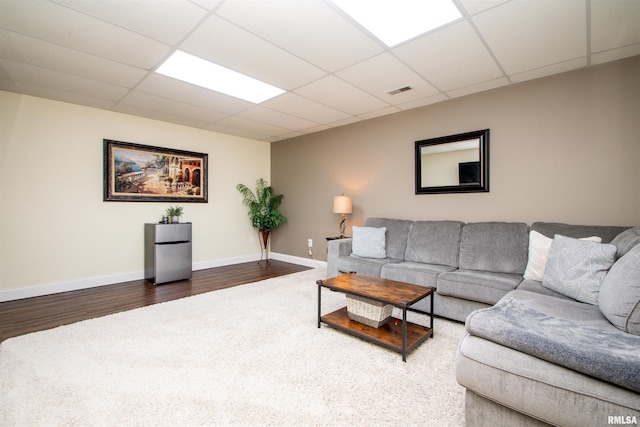 living room featuring a paneled ceiling, visible vents, baseboards, and wood finished floors