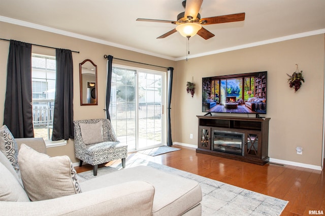 living area featuring a wealth of natural light, crown molding, and wood finished floors