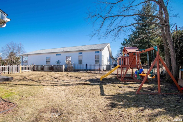 back of house featuring a playground, fence, brick siding, and a lawn