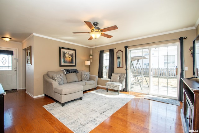 living room with crown molding, baseboards, and wood finished floors