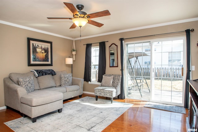 living room featuring ornamental molding, wood finished floors, a ceiling fan, and baseboards