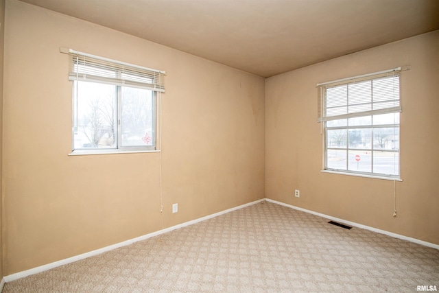 spare room with carpet, baseboards, and visible vents