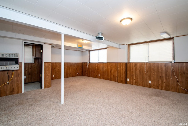 basement featuring heating unit, wood walls, carpet, and wainscoting