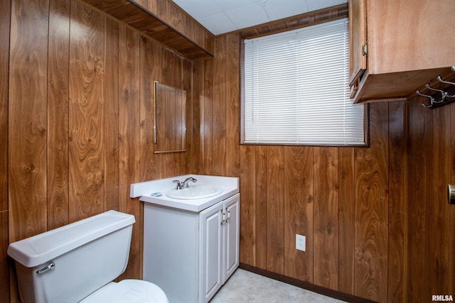 bathroom with wooden walls, toilet, and vanity