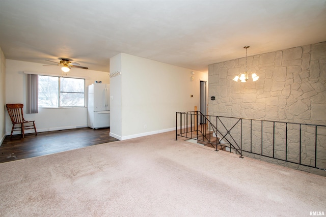 carpeted empty room featuring baseboards and ceiling fan with notable chandelier