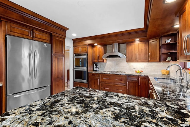 kitchen with a sink, tasteful backsplash, stainless steel appliances, dark stone counters, and wall chimney exhaust hood