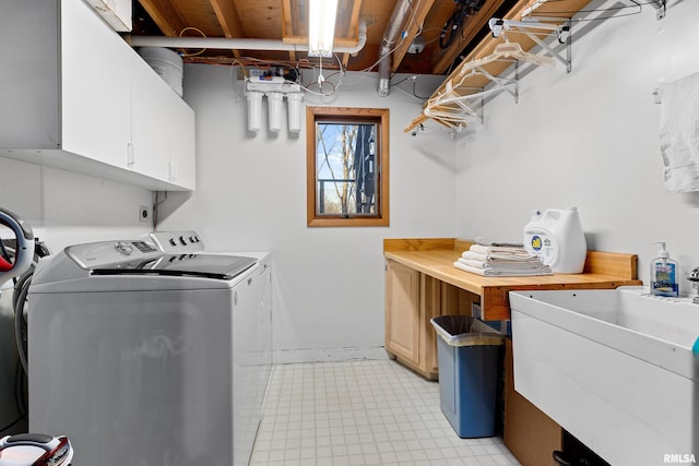 washroom featuring separate washer and dryer, cabinet space, and a sink