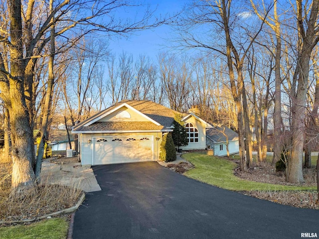 ranch-style home with roof with shingles, driveway, a chimney, a front lawn, and a garage