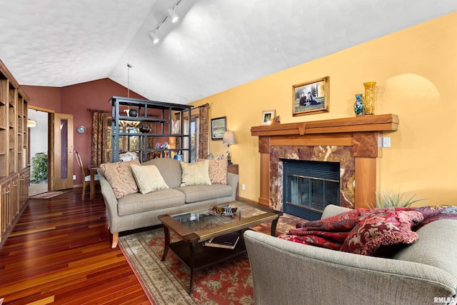 living area featuring a high end fireplace, track lighting, baseboards, lofted ceiling, and wood-type flooring