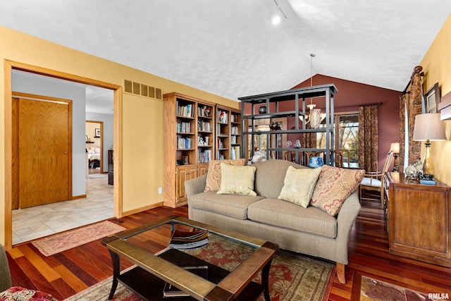 living room with wood finished floors, baseboards, visible vents, lofted ceiling, and a chandelier