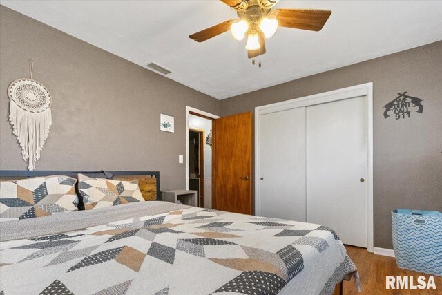 bedroom featuring a closet, wood finished floors, visible vents, and a ceiling fan