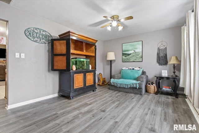 living area with ceiling fan, wood finished floors, and baseboards