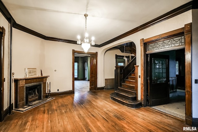 interior space with stairway, wood finished floors, a premium fireplace, arched walkways, and ornamental molding