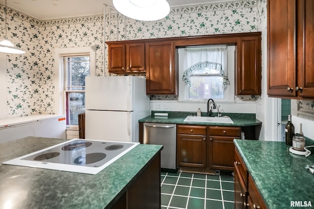 kitchen featuring white appliances, a healthy amount of sunlight, dark countertops, and a sink