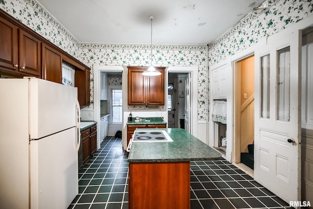 kitchen with dark countertops, a center island, wallpapered walls, freestanding refrigerator, and dark tile patterned flooring