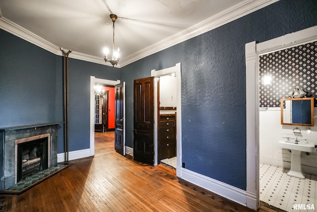 unfurnished bedroom featuring hardwood / wood-style floors, a fireplace, crown molding, baseboards, and a textured wall