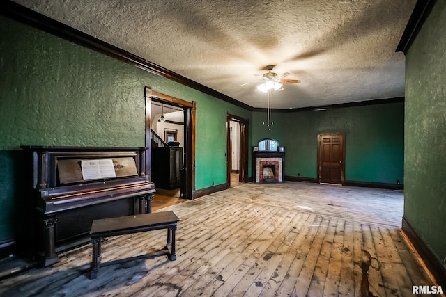 unfurnished room featuring ornamental molding, a textured ceiling, hardwood / wood-style floors, ceiling fan, and a textured wall