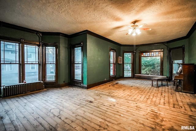 interior space featuring ornamental molding, a textured ceiling, radiator heating unit, and wood-type flooring