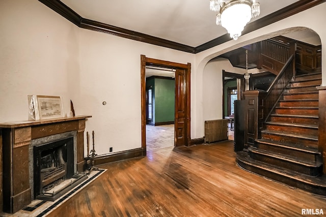 unfurnished living room featuring wood finished floors, a high end fireplace, stairway, arched walkways, and baseboards