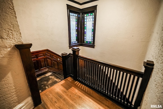 stairway featuring wood finished floors and a textured wall