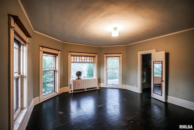 empty room with ornamental molding, radiator heating unit, baseboards, and wood finished floors