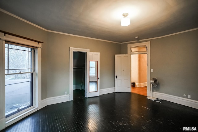 spare room with crown molding, baseboards, and wood-type flooring