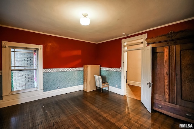 spare room featuring a wainscoted wall, wood-type flooring, and ornamental molding