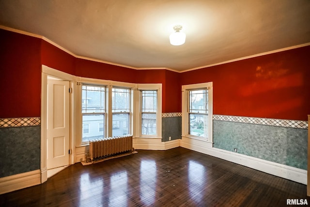 spare room with a wainscoted wall, radiator, crown molding, and wood finished floors