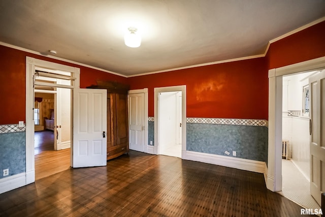 unfurnished bedroom with radiator, baseboards, wallpapered walls, dark wood-style flooring, and crown molding