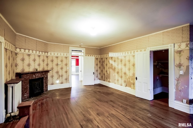 unfurnished living room featuring baseboards, dark wood-type flooring, crown molding, and wallpapered walls