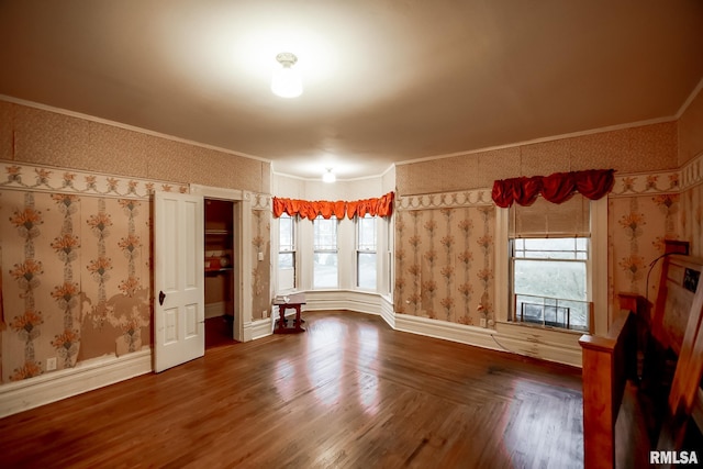 spare room featuring baseboards, ornamental molding, and wallpapered walls