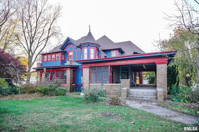 victorian home featuring a front yard, a porch, and brick siding