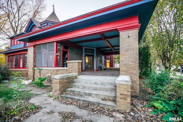 view of front of house featuring brick siding and a porch