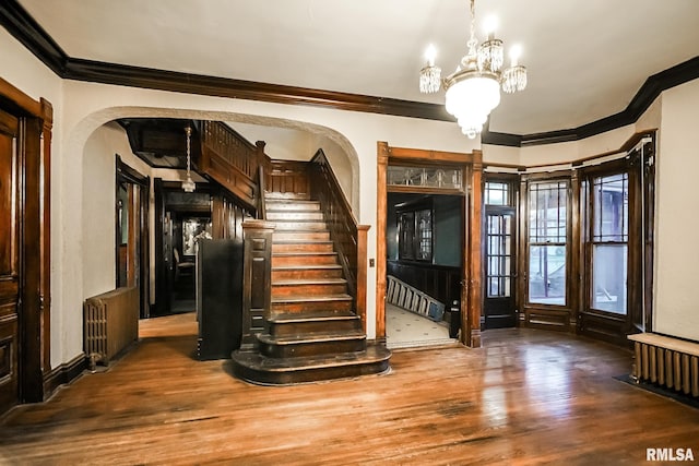 entrance foyer featuring stairs, wood finished floors, arched walkways, and a chandelier