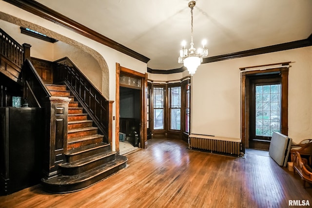 entrance foyer with radiator, crown molding, a chandelier, stairway, and wood finished floors