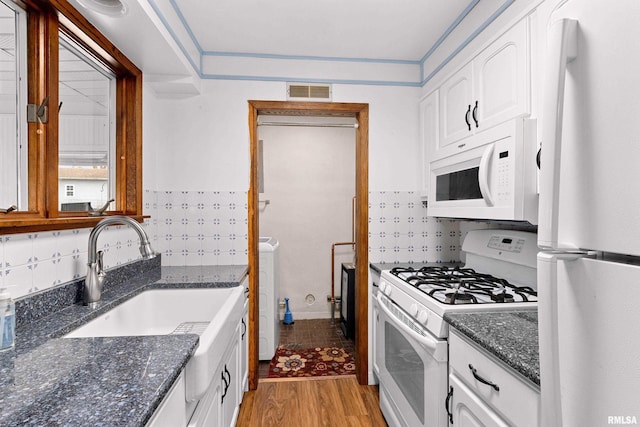 kitchen with light wood finished floors, visible vents, white appliances, white cabinetry, and a sink