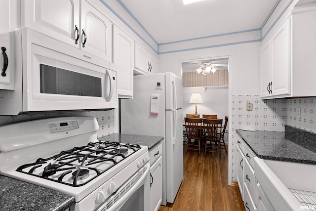 kitchen featuring white appliances, light wood-type flooring, dark stone counters, white cabinets, and tasteful backsplash