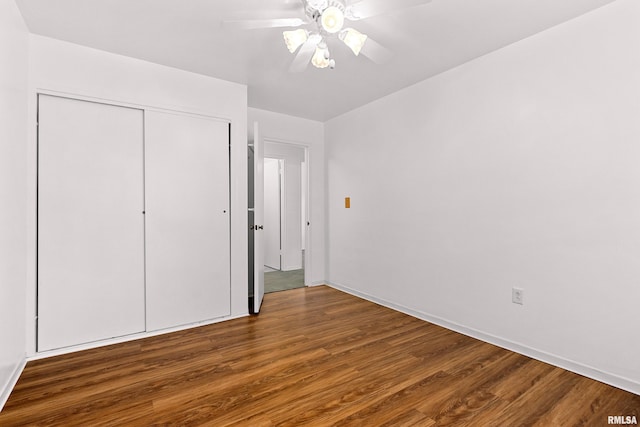 unfurnished bedroom featuring a closet, baseboards, wood finished floors, and a ceiling fan