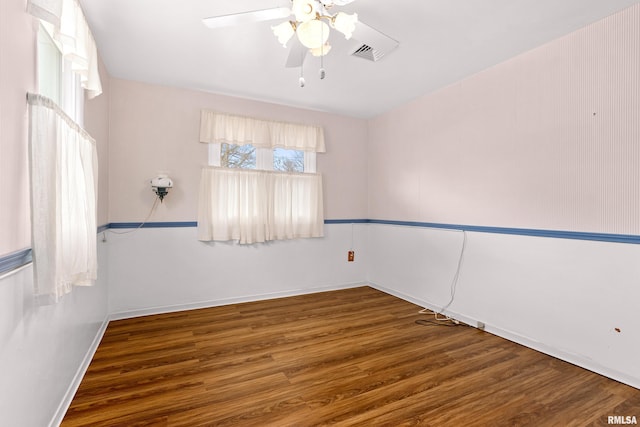 spare room featuring visible vents, baseboards, wood finished floors, and a ceiling fan