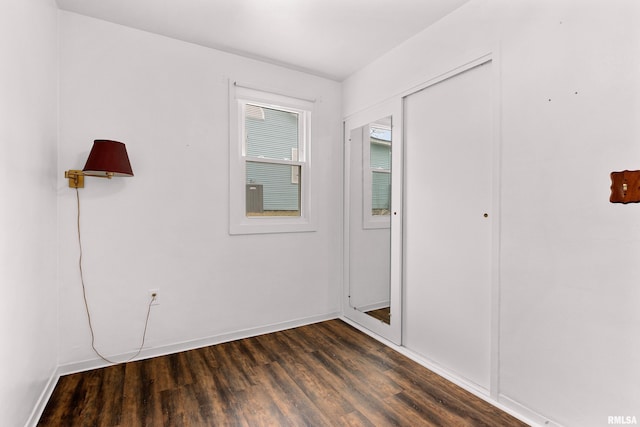 unfurnished bedroom with a closet, baseboards, and dark wood-style flooring