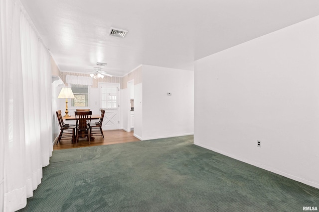 unfurnished dining area featuring baseboards, carpet, visible vents, and ceiling fan